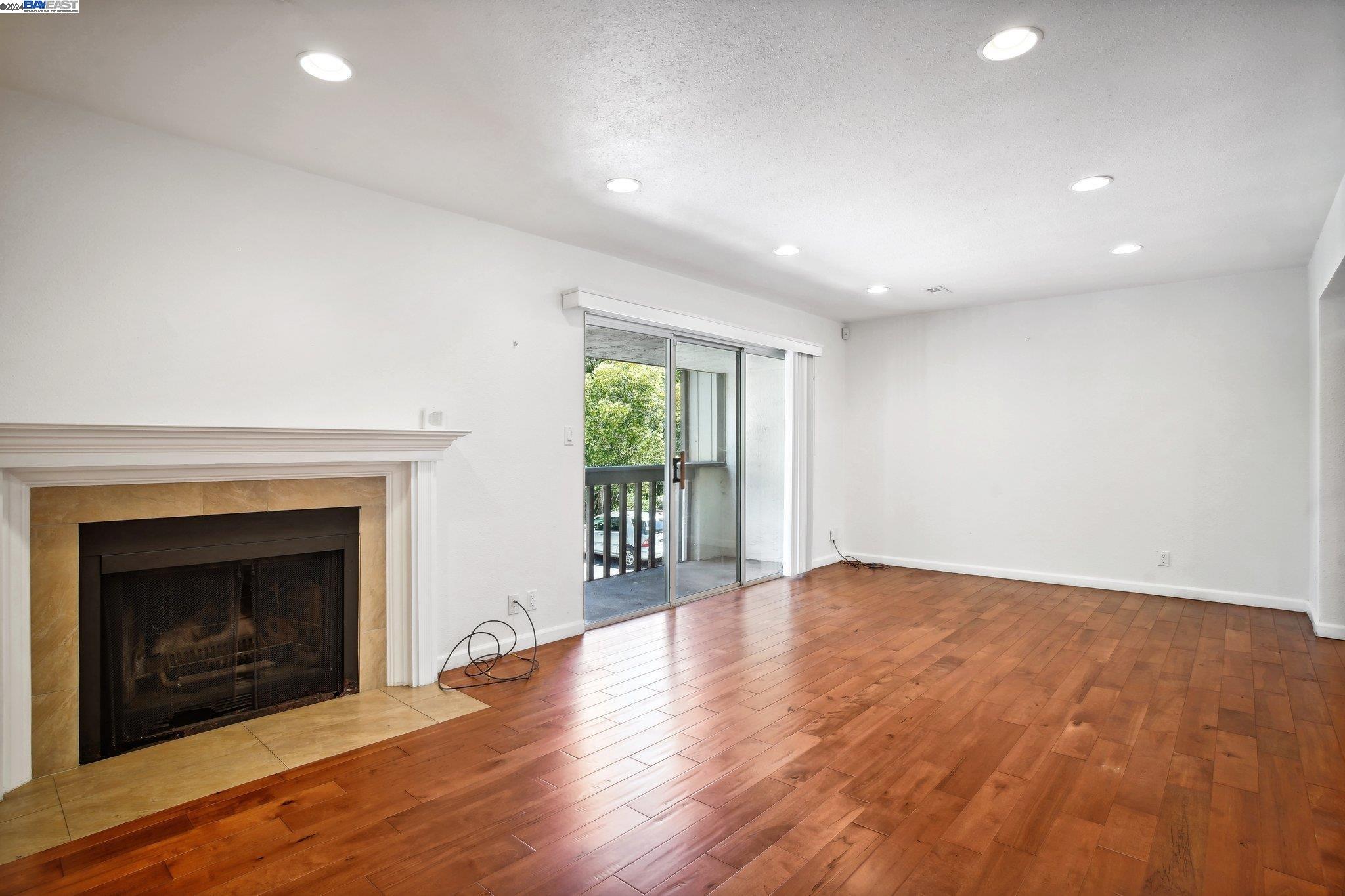 an empty room with wooden floor fireplace and windows