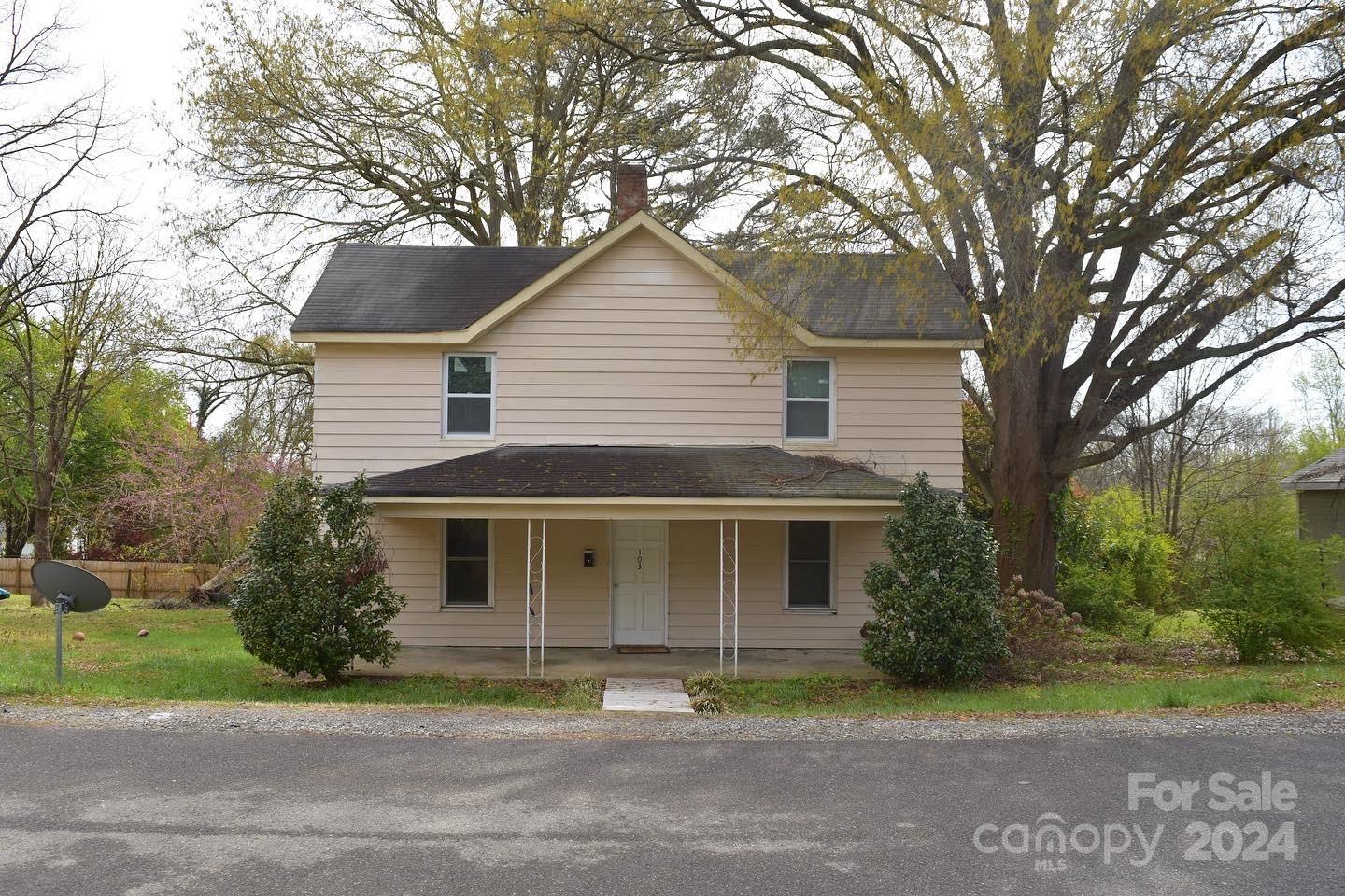 a front view of a house with a garden and trees