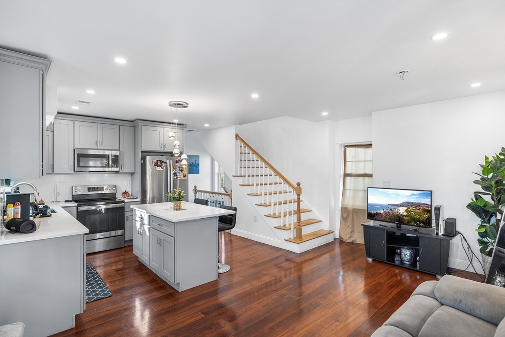 a living room with stainless steel appliances furniture and wooden floor