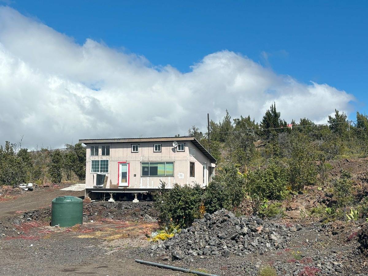 a front view of house with yard and trees in the background