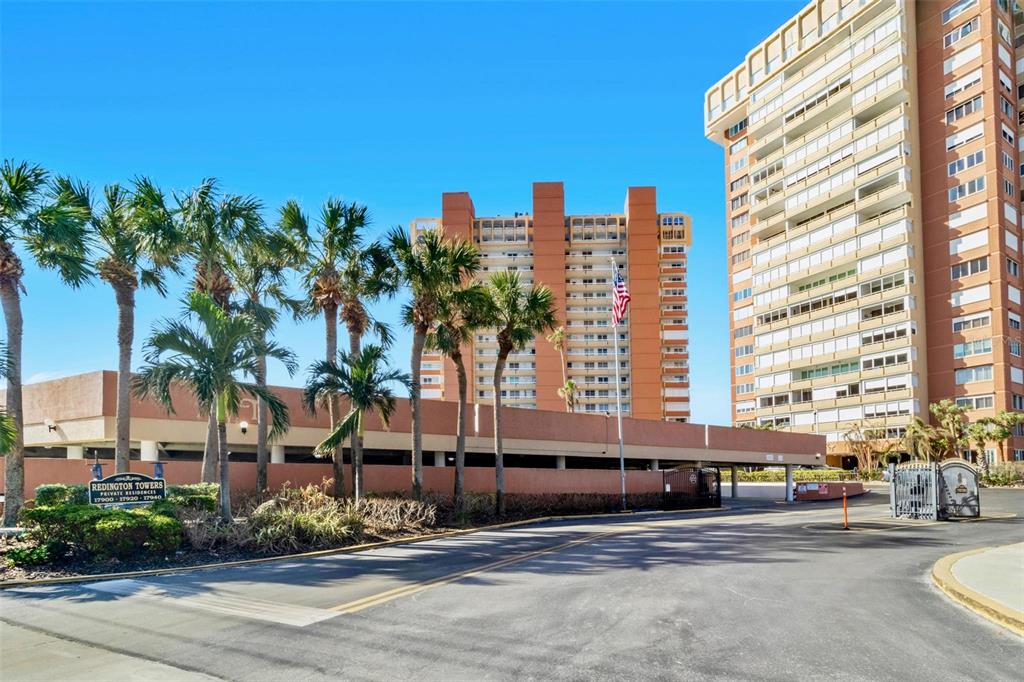 a front view of a multi story residential apartment building with yard and parking space