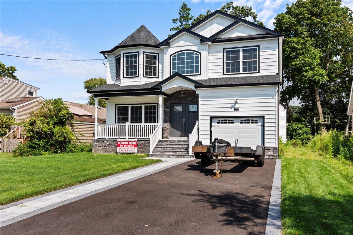 View of front of property featuring a porch, a garage, and a front lawn