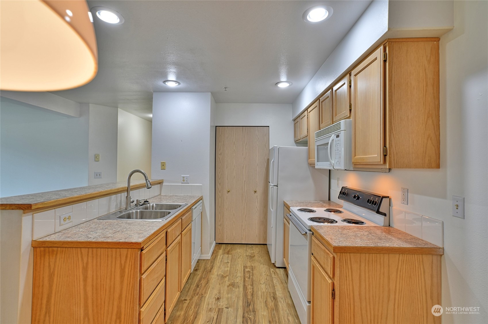 a kitchen with a sink a stove cabinets and a wooden floor