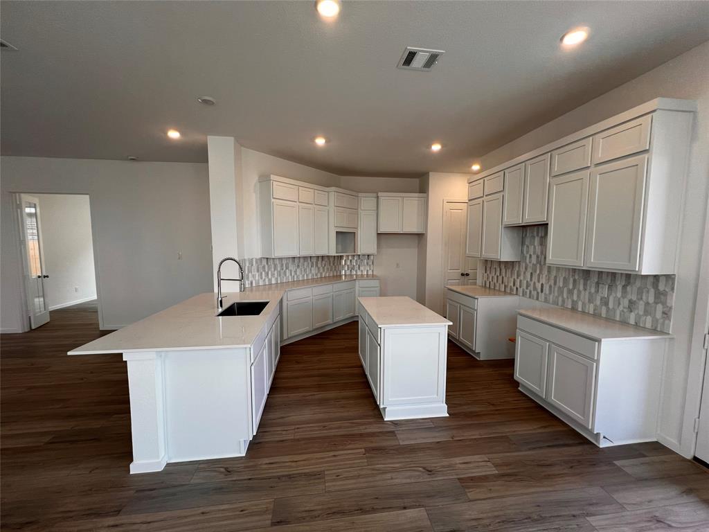 a large kitchen with kitchen island a white wooden cabinets and living room