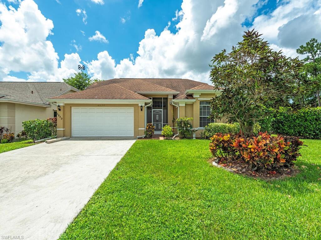 Ranch-style house featuring a garage and a front lawn