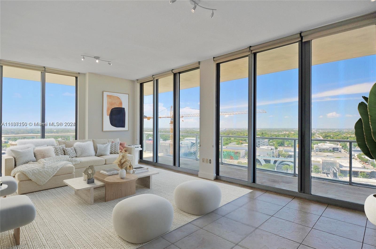 a large living room with furniture and floor to ceiling windows