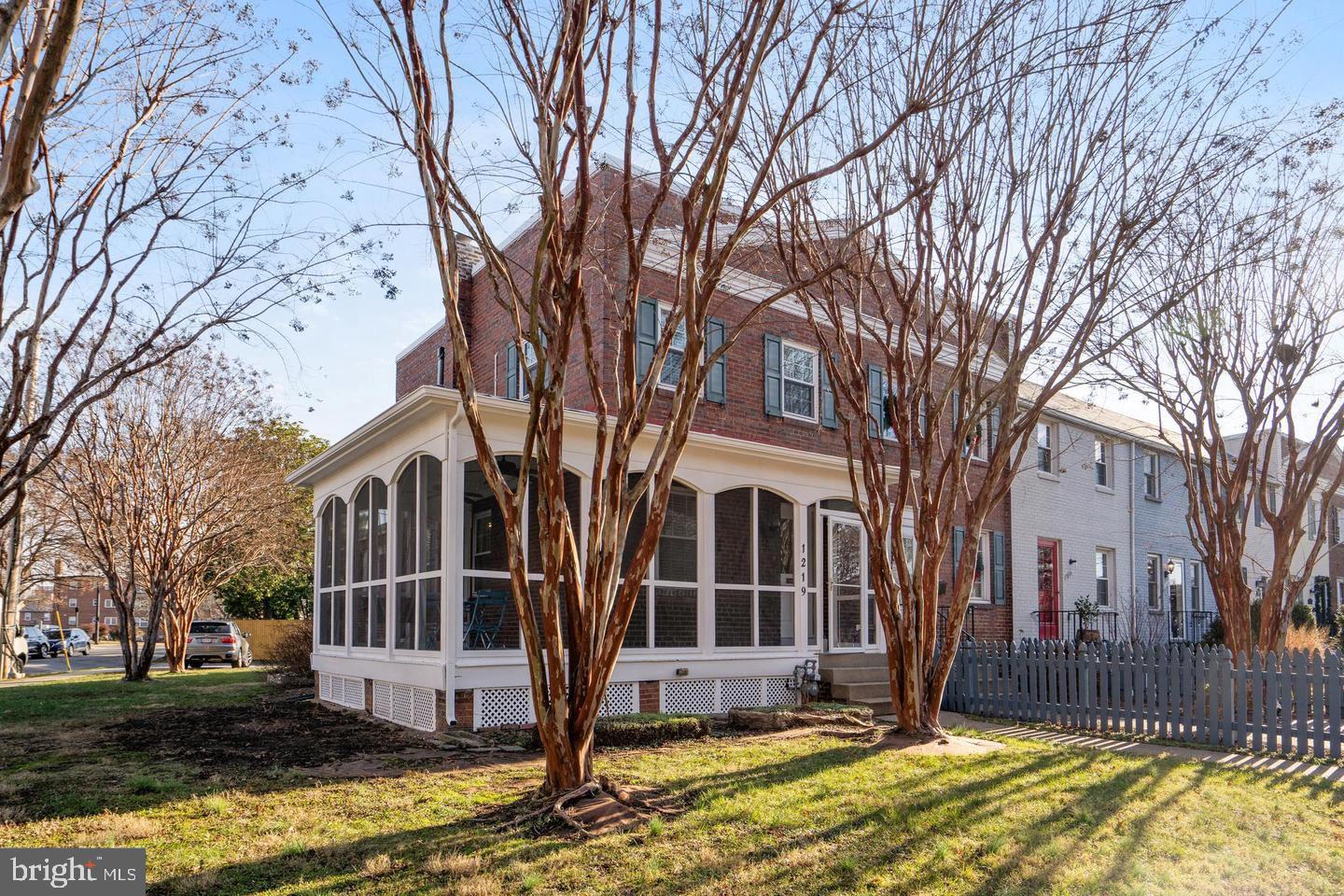 a front view of a house with a yard large tree and wooden fence