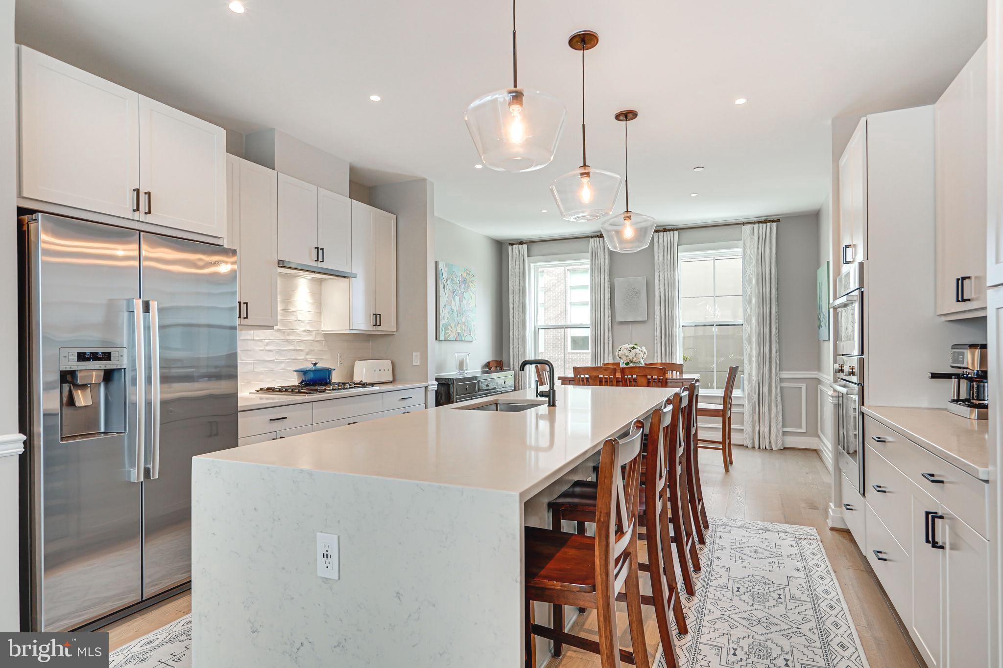 a kitchen with stainless steel appliances a refrigerator a sink a stove and white cabinets