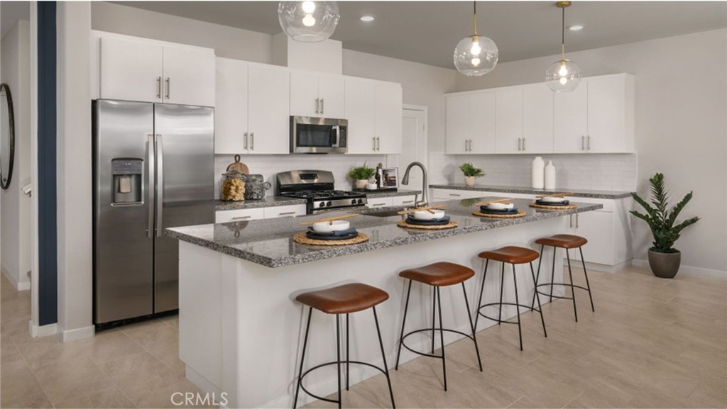 a kitchen with stainless steel appliances a table chairs refrigerator and microwave