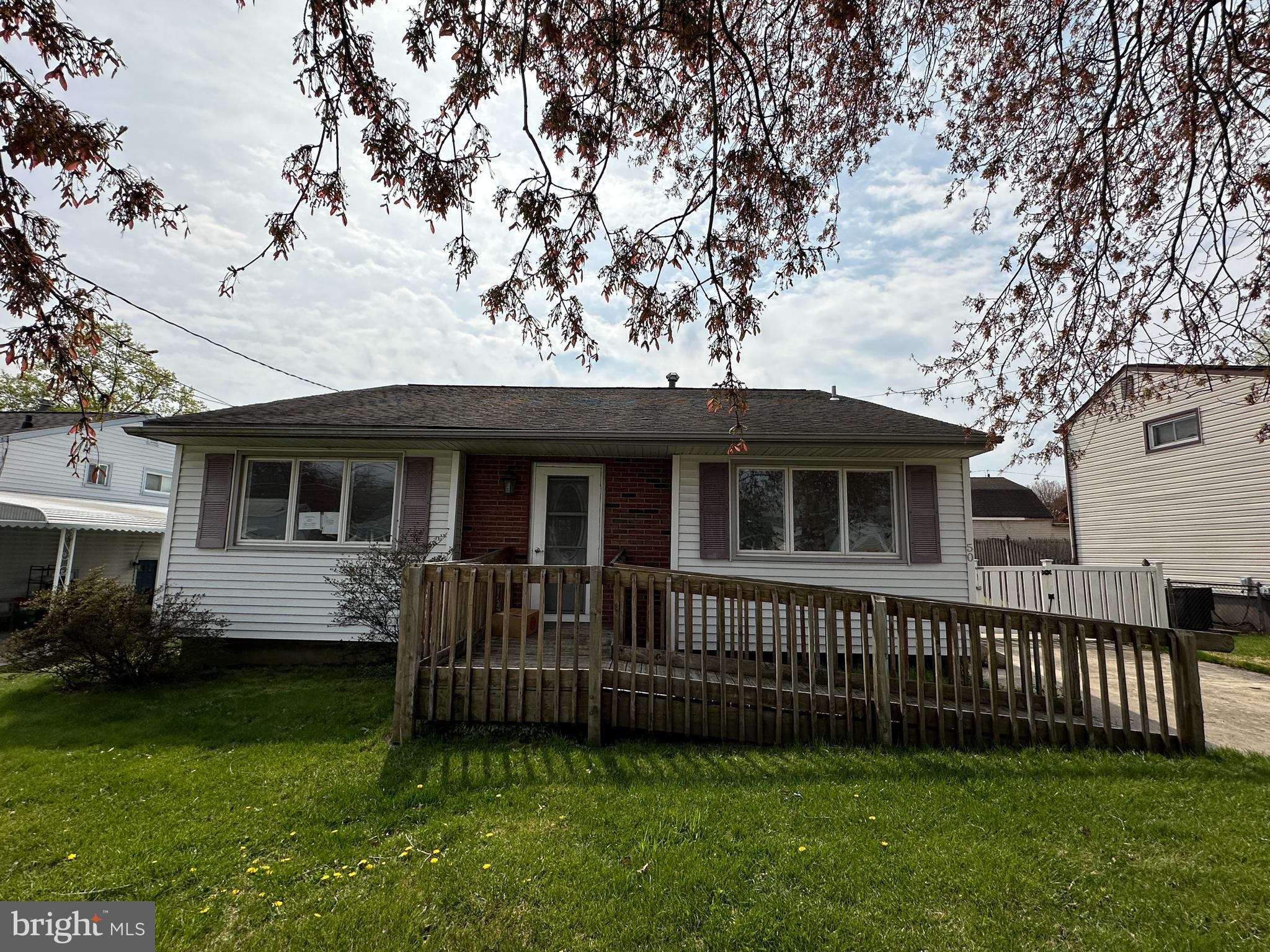 a view of a house with a deck and a yard with a large tree