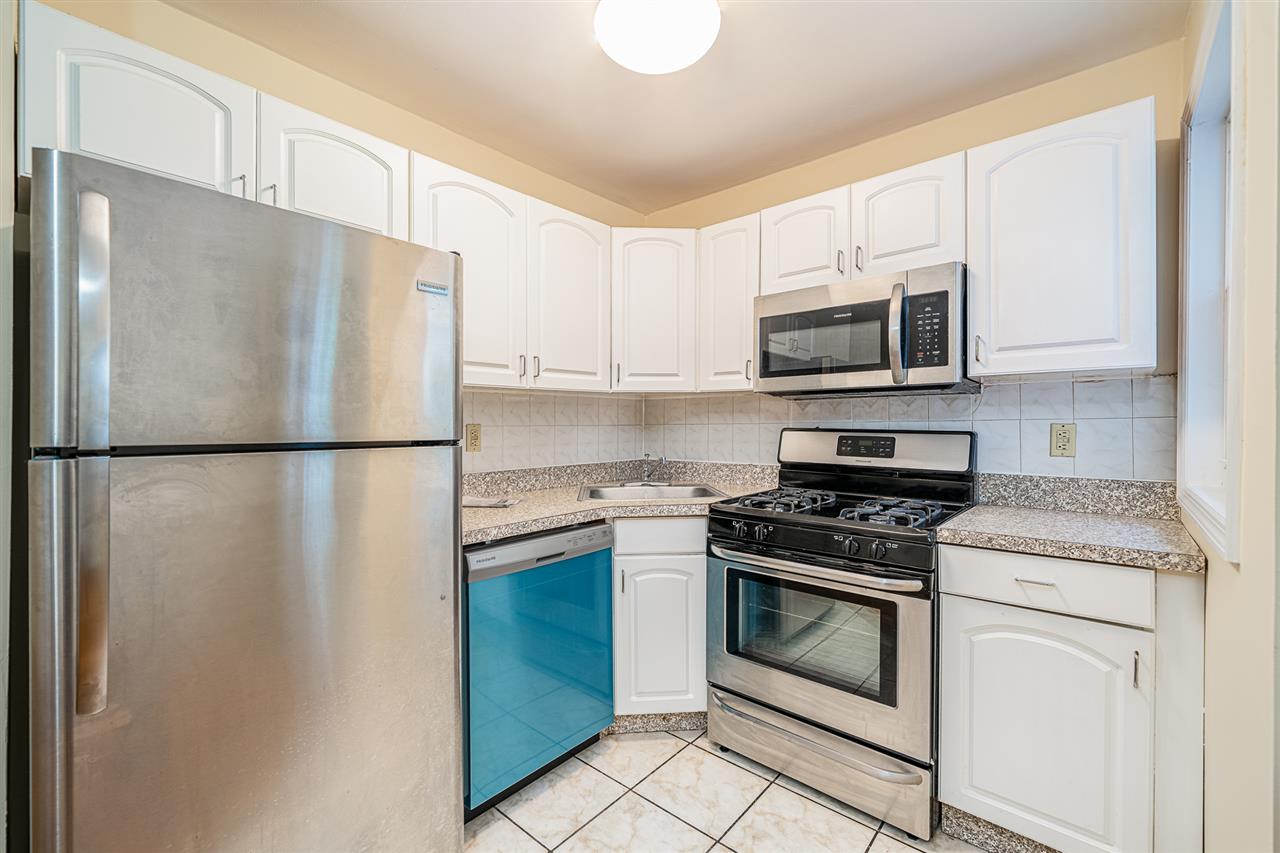 a kitchen with stainless steel appliances white cabinets white stove a microwave and a refrigerator