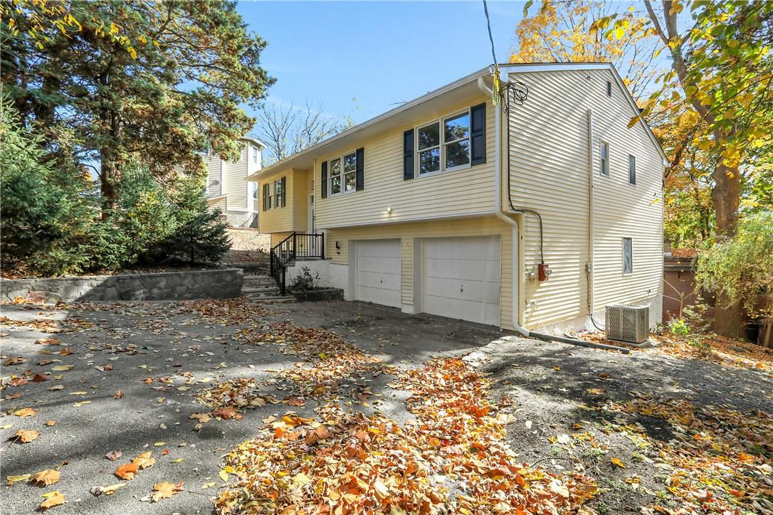 View of property exterior with cooling unit and a garage