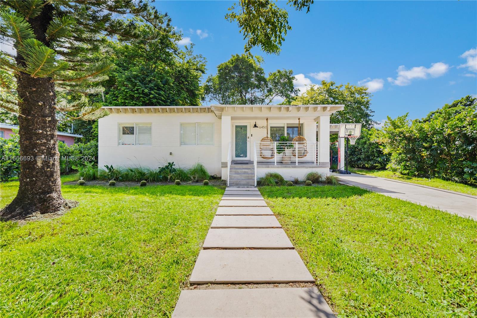 a front view of a house with a yard and potted plants