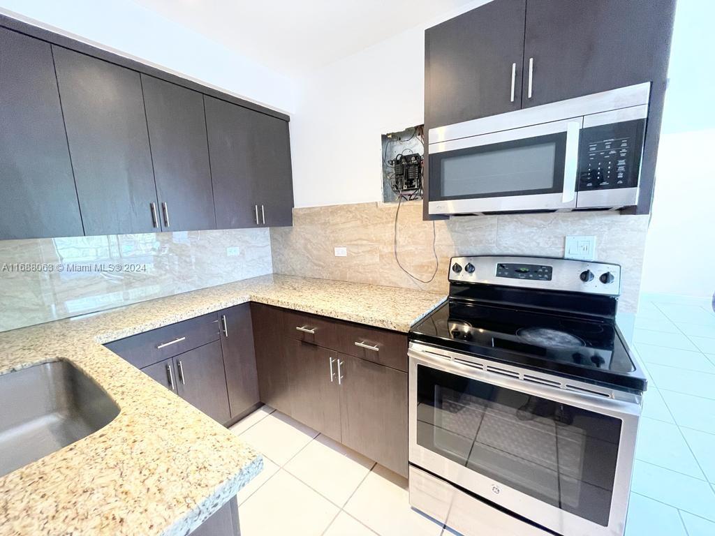 a kitchen with granite countertop a stove and a microwave