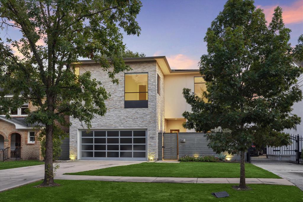 Modern elegance meets contemporary charm in this beautifully designed home, featuring a striking stone façade and expansive windows, nestled on a tree-lined street.