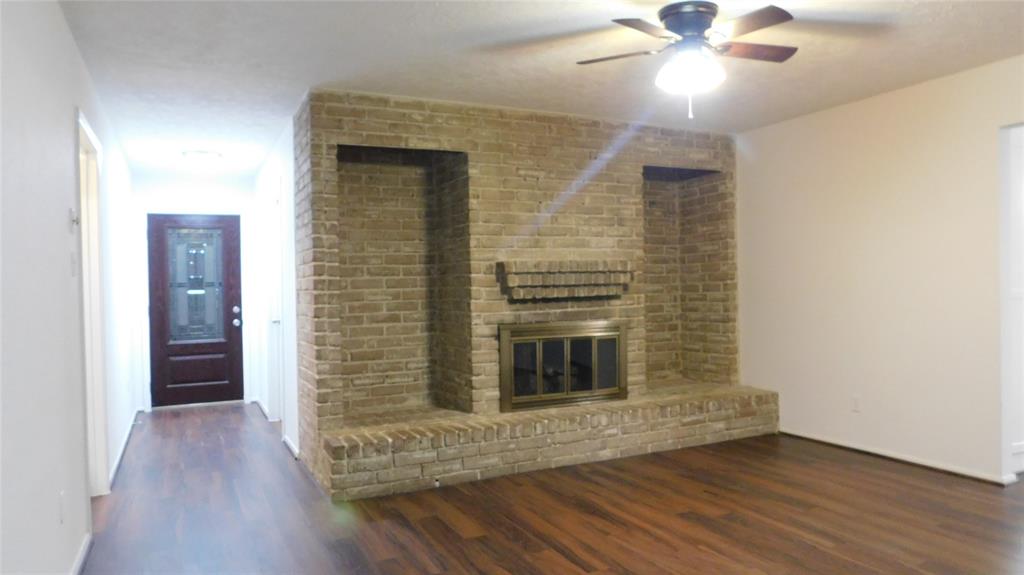 a view of a livingroom with wooden floor a ceiling fan and a bathroom