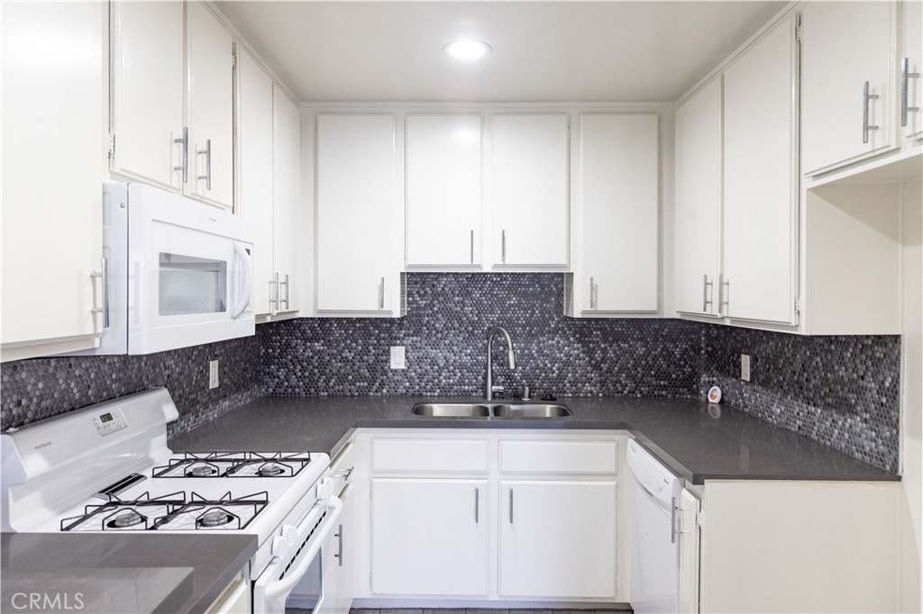 a kitchen with granite countertop a sink stove and cabinets