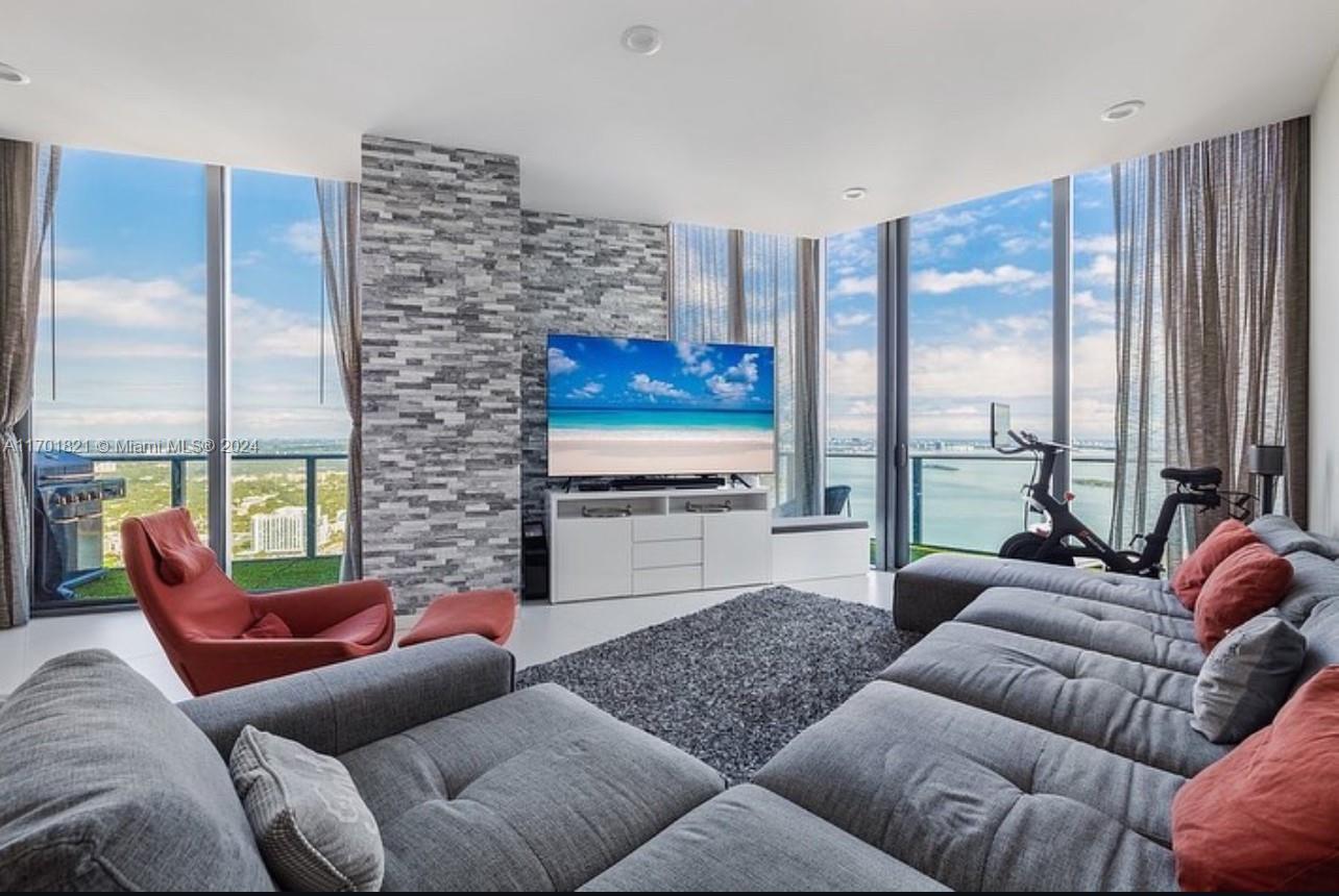 a living room with furniture ceiling fan and a large window