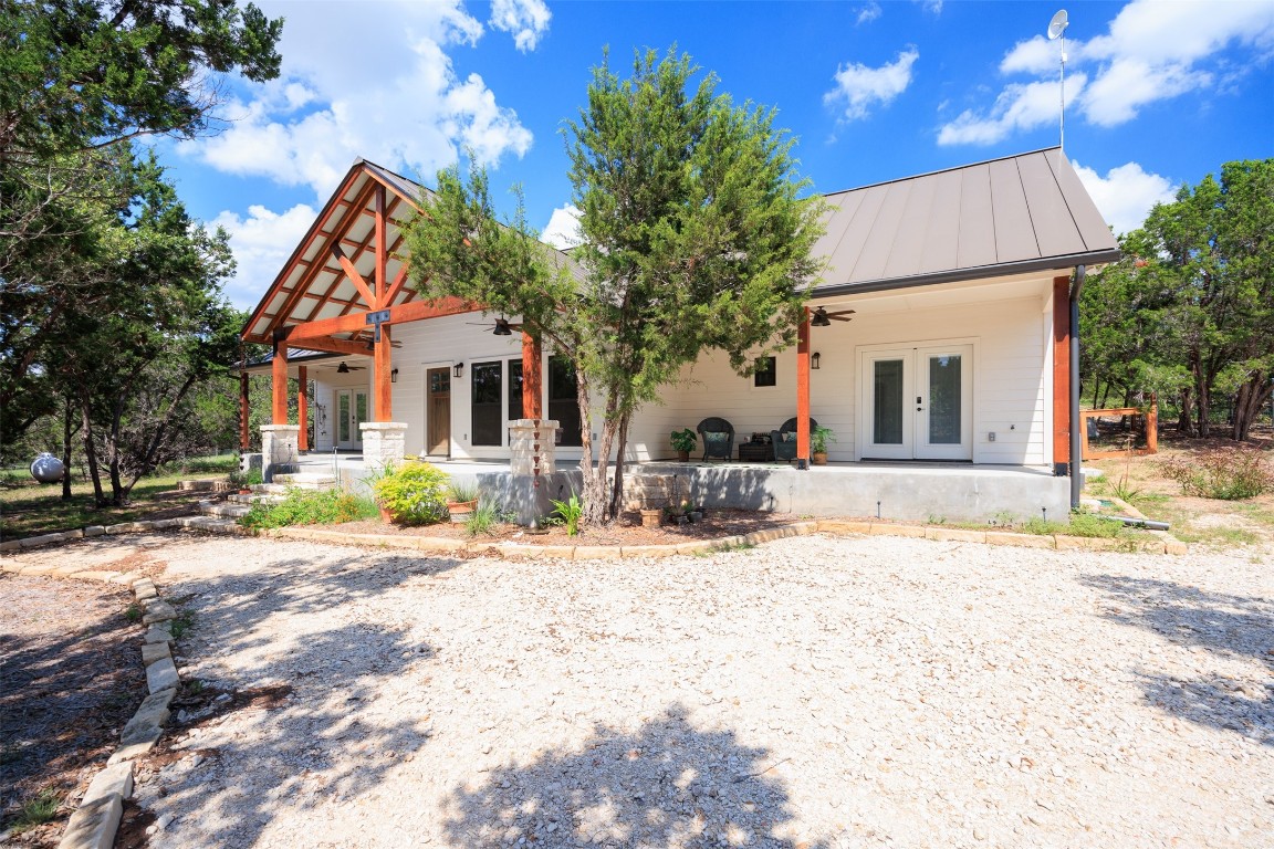 a front view of a house with a dirt yard and a large tree