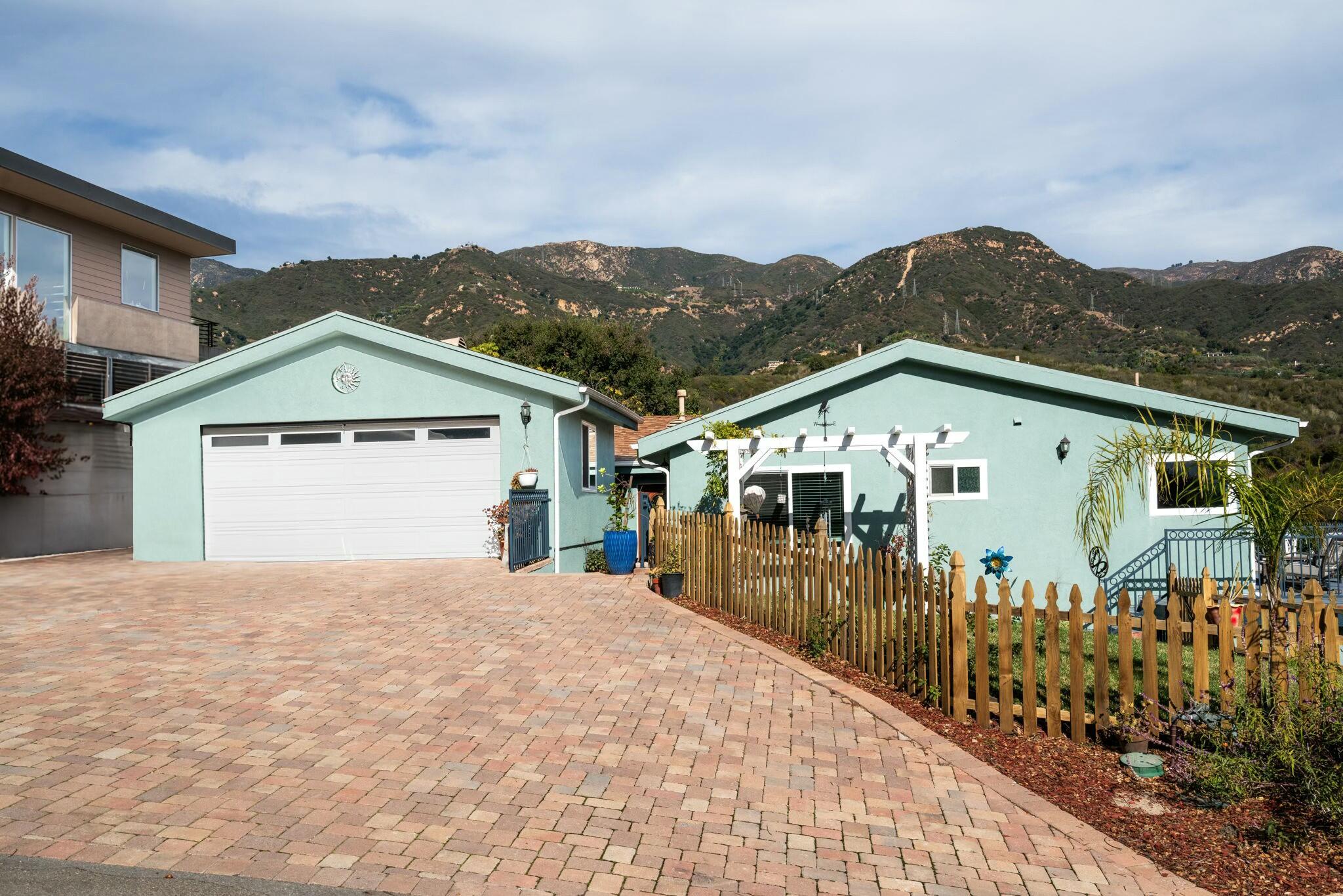 a front view of a house with a yard and mountain view in back