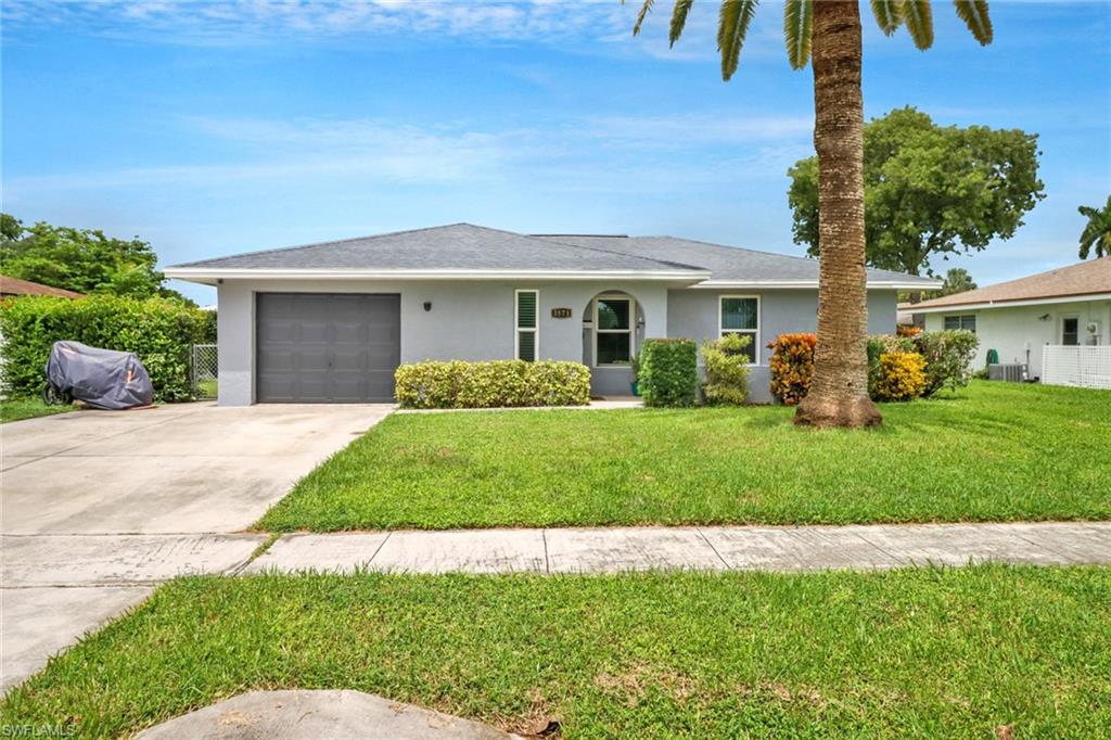 Ranch-style house featuring a garage and a front yard