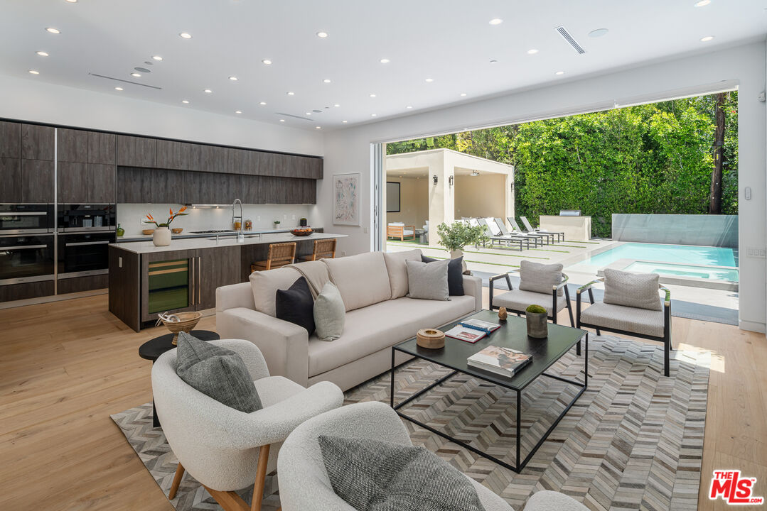 a living room with furniture kitchen view and a large window