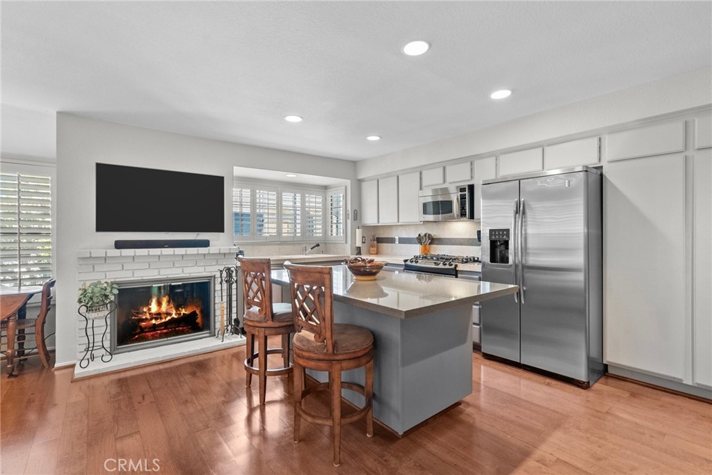 a kitchen with a refrigerator a stove top oven a fireplace and wooden floor