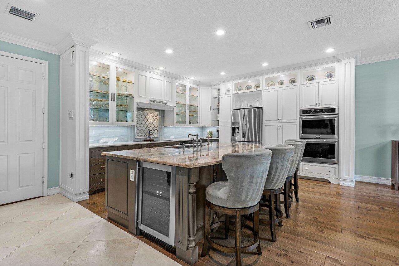 a kitchen with kitchen island granite countertop a dining table chairs stainless steel appliances and cabinets