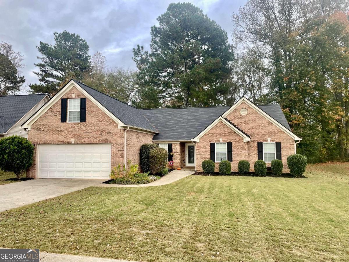 a front view of house with yard and trees in the background