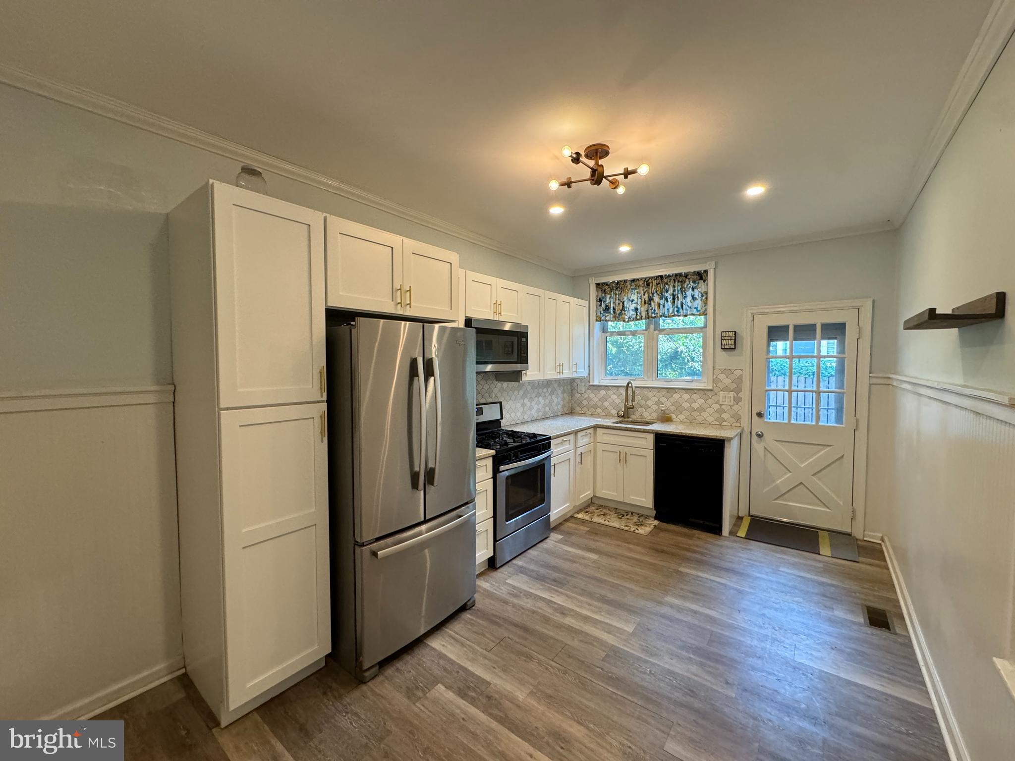 a kitchen with granite countertop stainless steel appliances a refrigerator cabinets and wooden floor