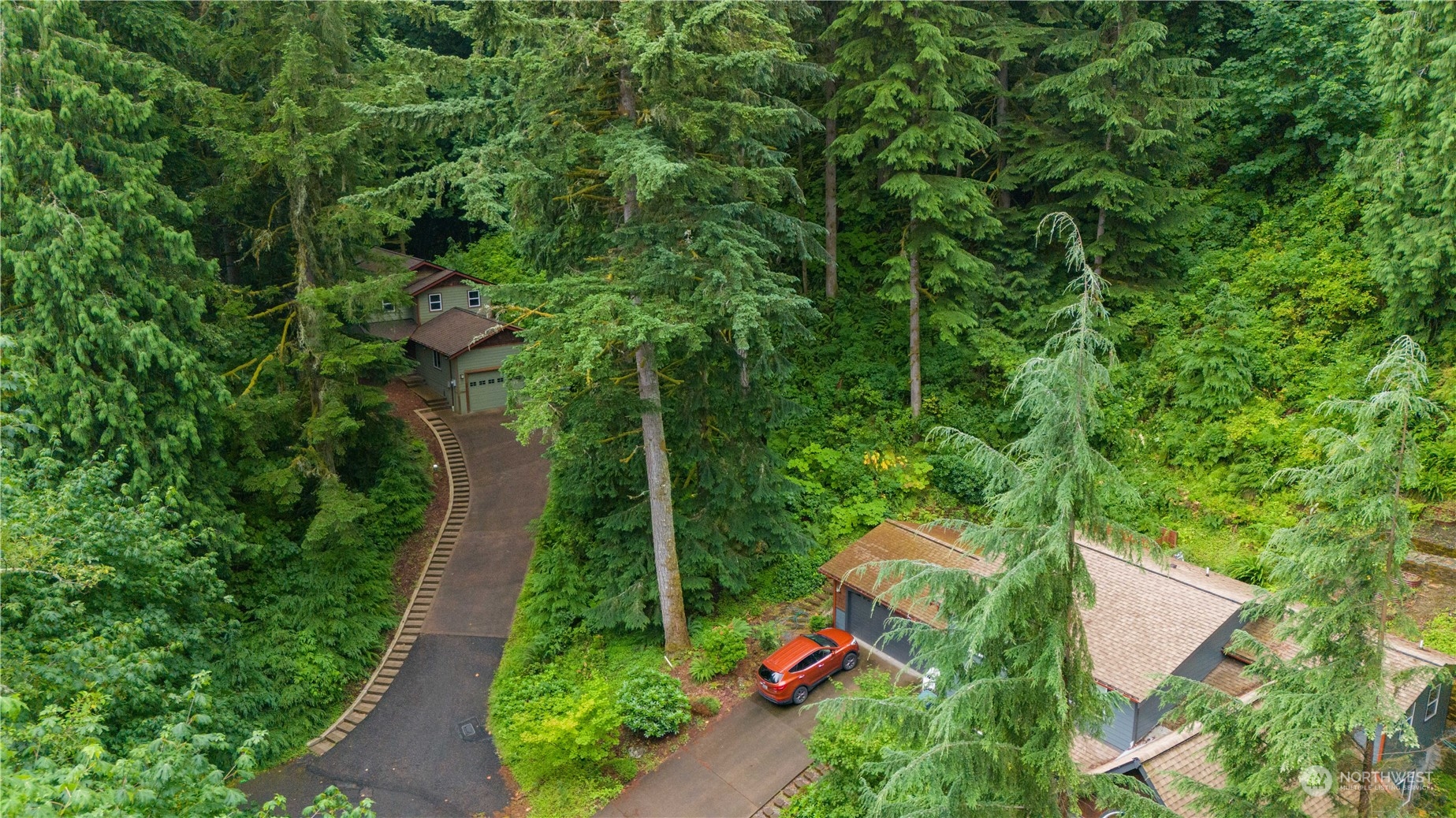 an aerial view of residential house with outdoor space and trees all around