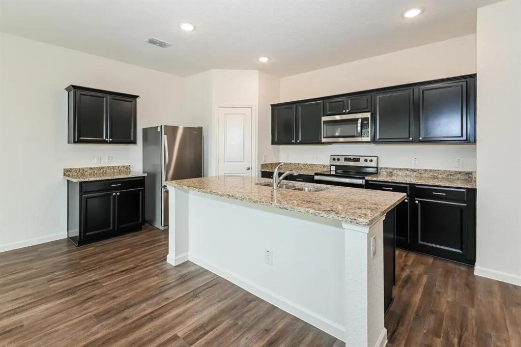 a kitchen with kitchen island granite countertop stainless steel appliances and wooden cabinets