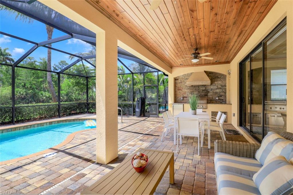 View of pool with ceiling fan, glass enclosure, and a patio