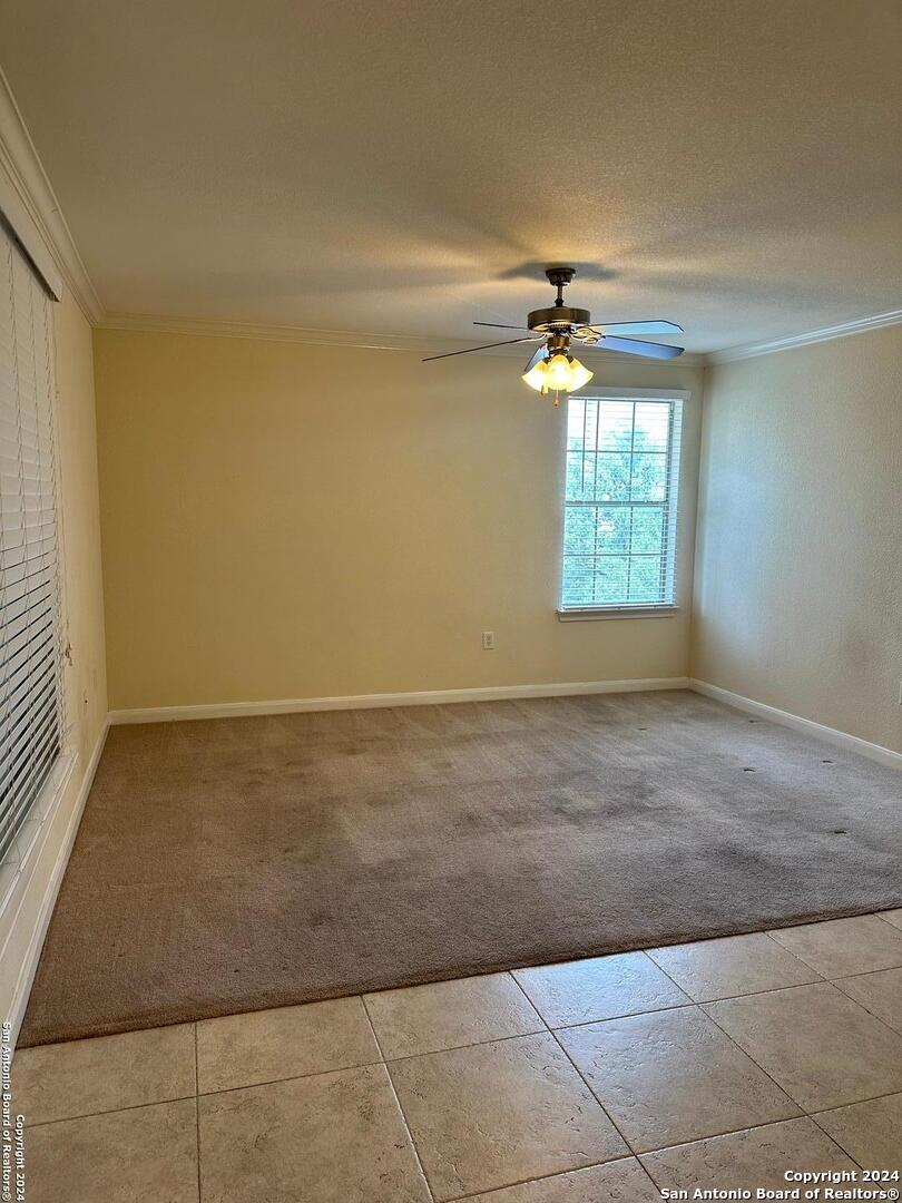 an empty room with windows and chandelier fan