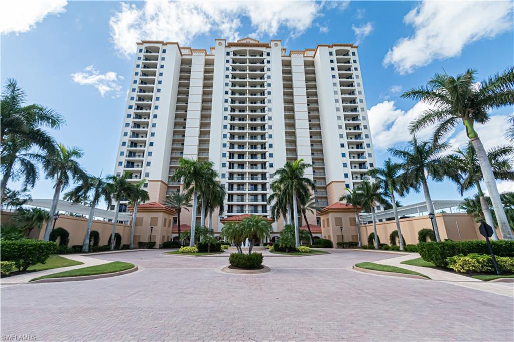 a front view of multi story residential apartment building with a yard and palm trees