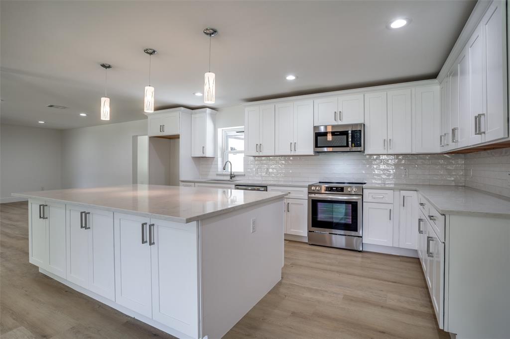 a kitchen with kitchen island granite countertop white cabinets and stainless steel appliances