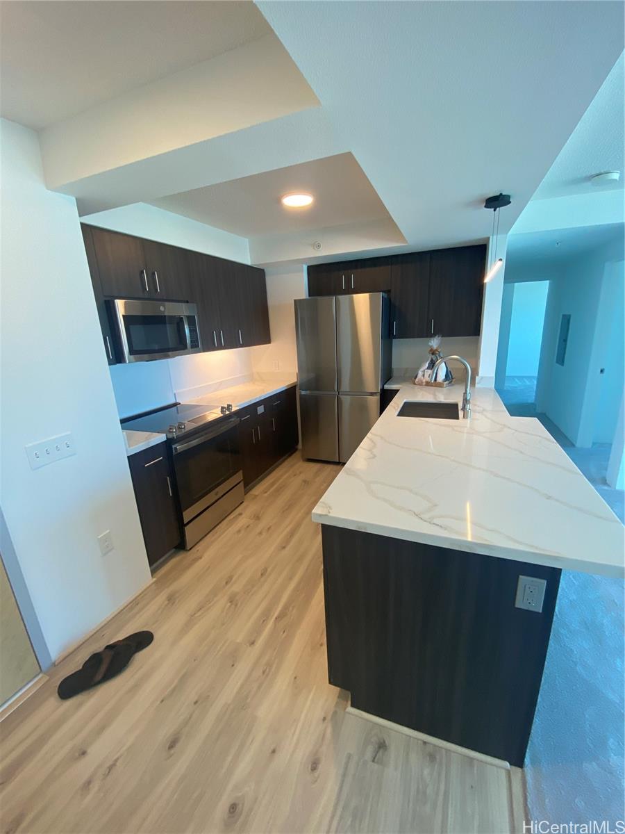 a kitchen with kitchen island stainless steel appliances a sink cabinets and wooden floor