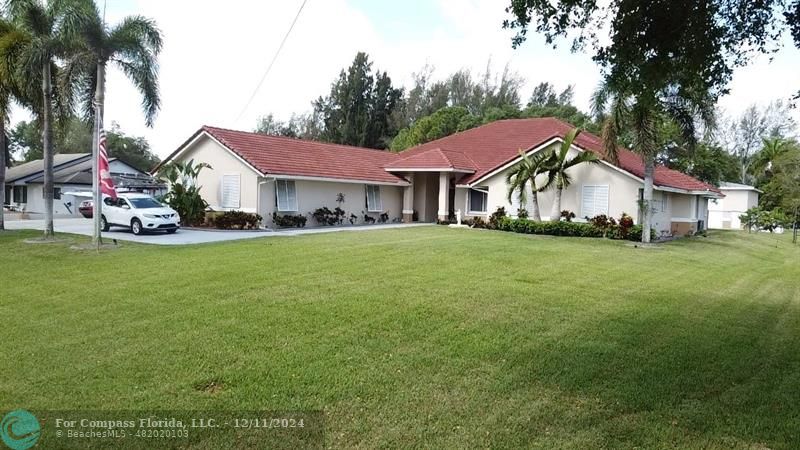 a view of a house with a big yard and large trees