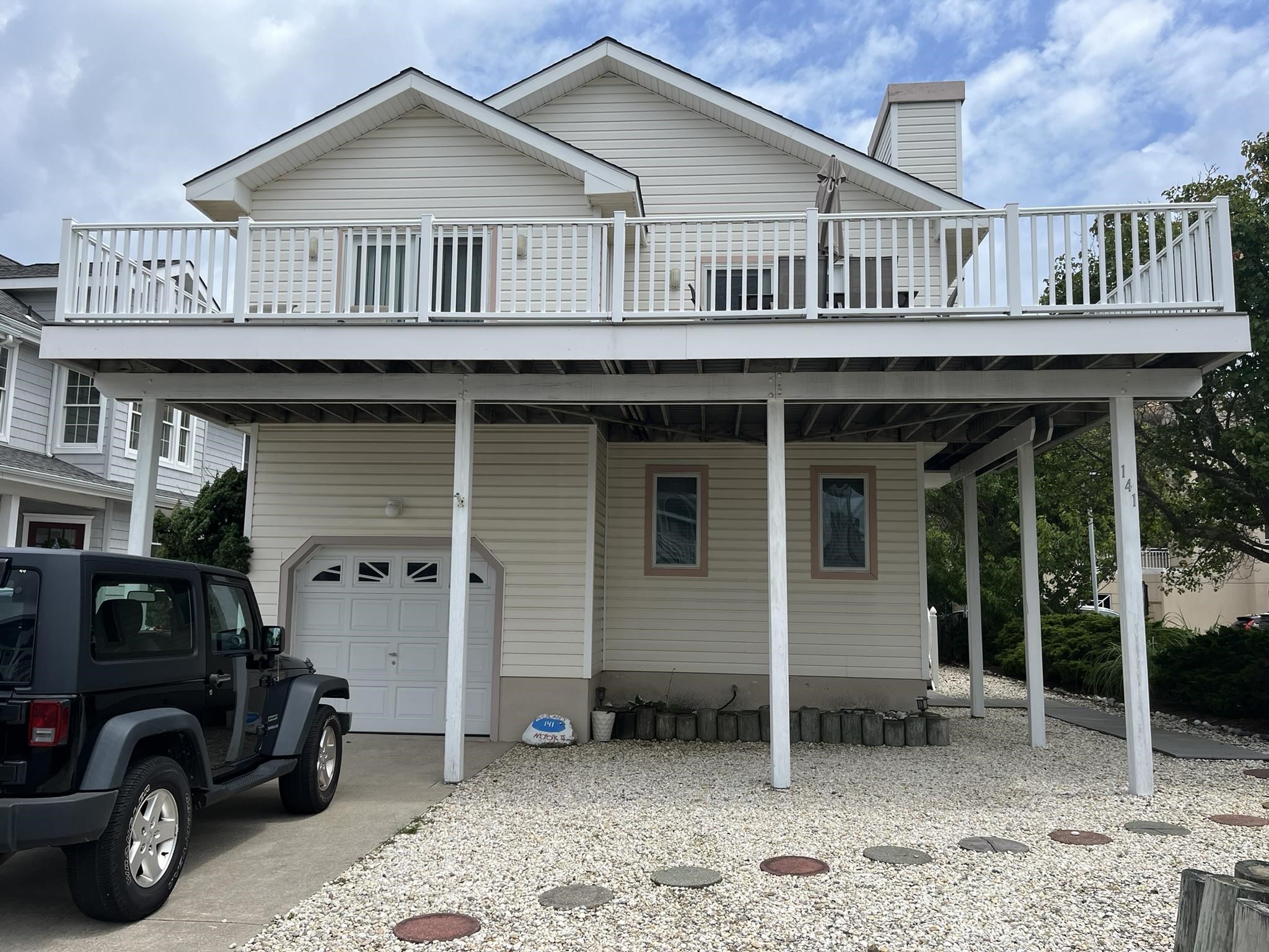 a view of a house with a wooden deck and a car parked in front of it