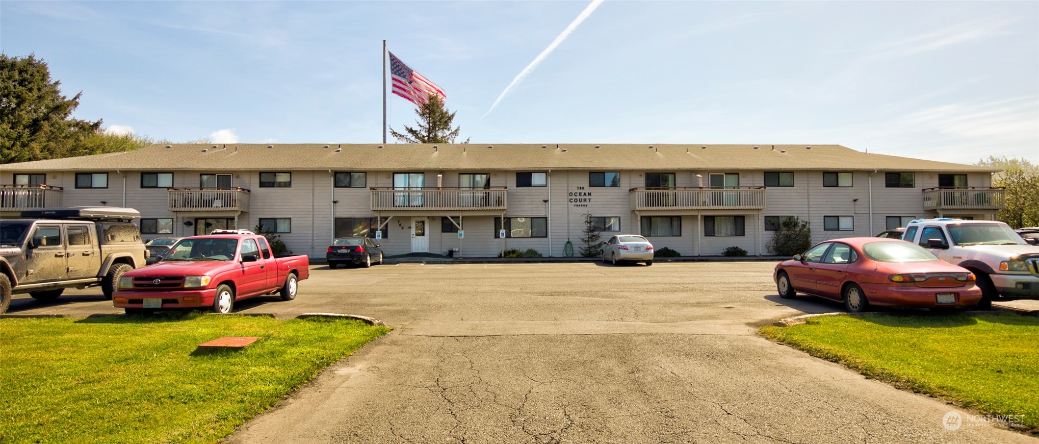 a front view of a building with cars parked