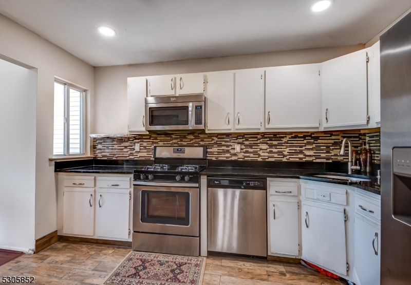 a kitchen with granite countertop a stove sink and cabinets