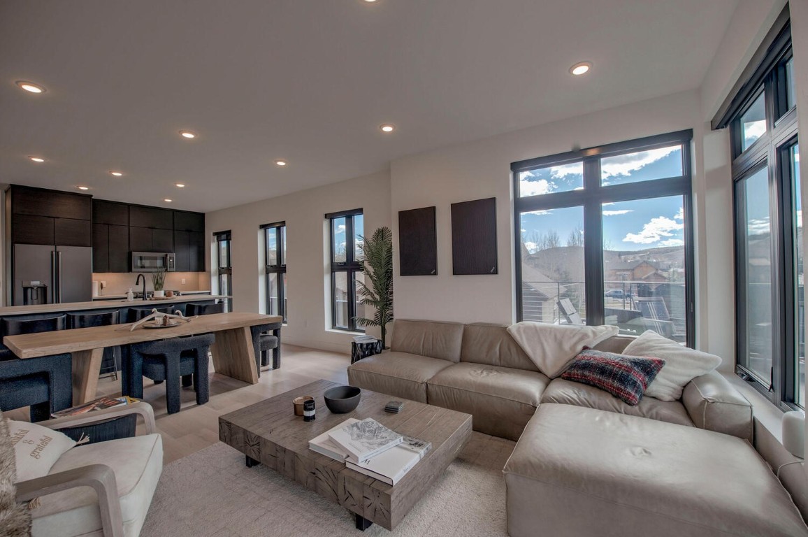 a living room with furniture kitchen view and large windows