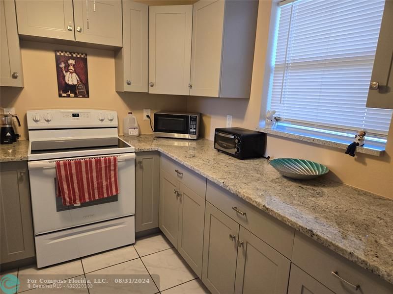 a kitchen with granite countertop a sink a stove and cabinets