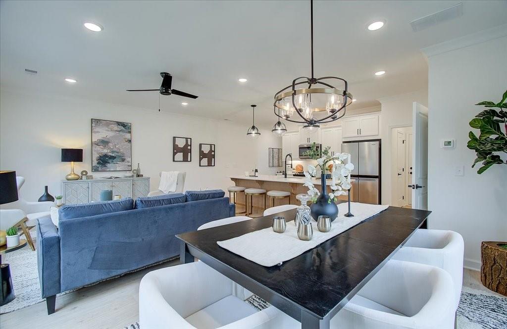 a living room with couches a dining table and a chandelier with wooden floor