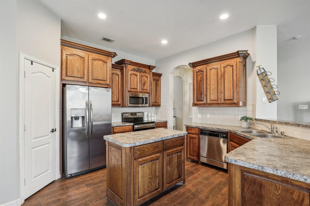 Kitchen with kitchen peninsula, stainless steel appliances, dark wood-type flooring, and sink