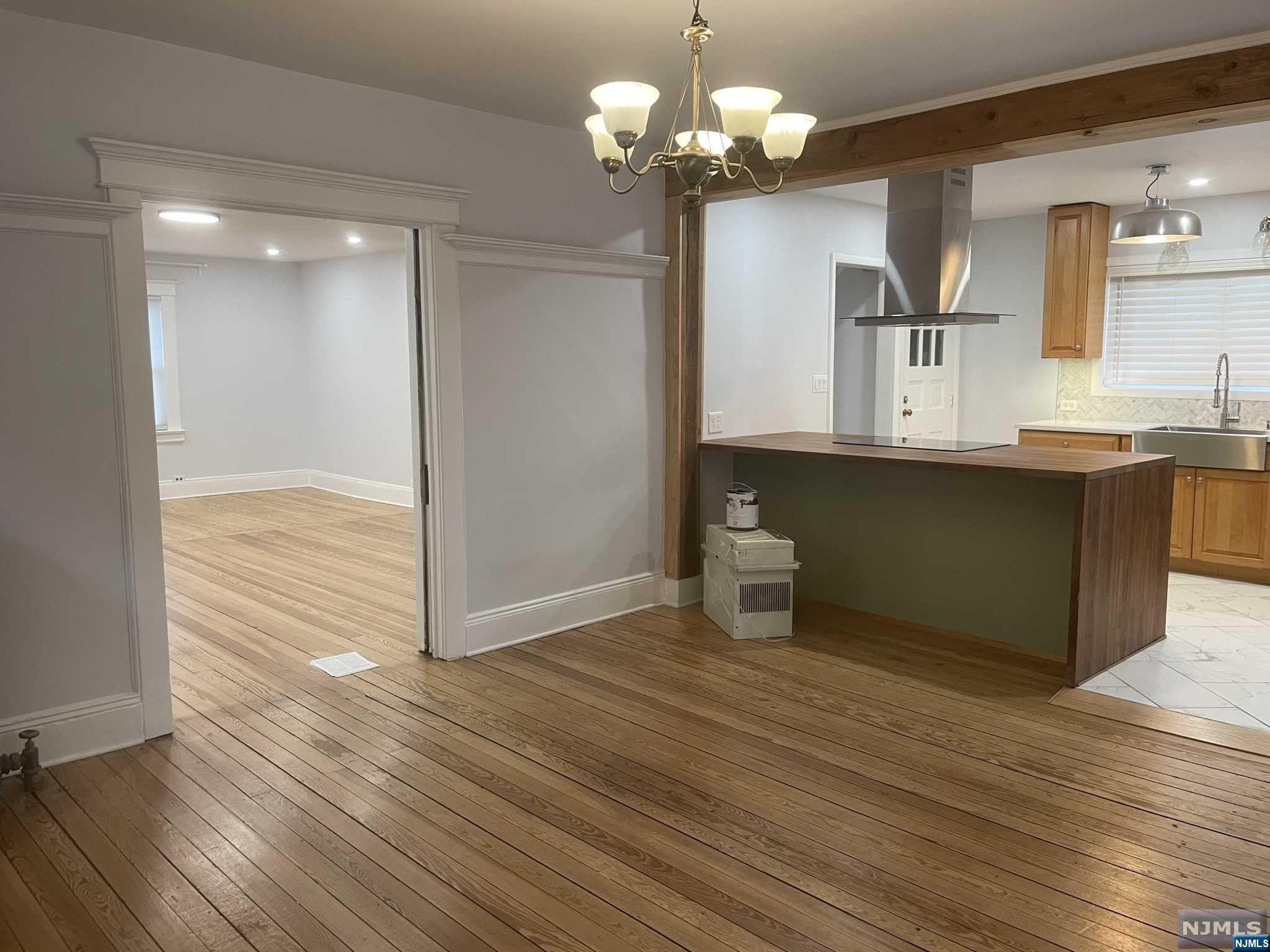 a view of a kitchen with a dishwasher a kitchen island hardwood floor and a sink