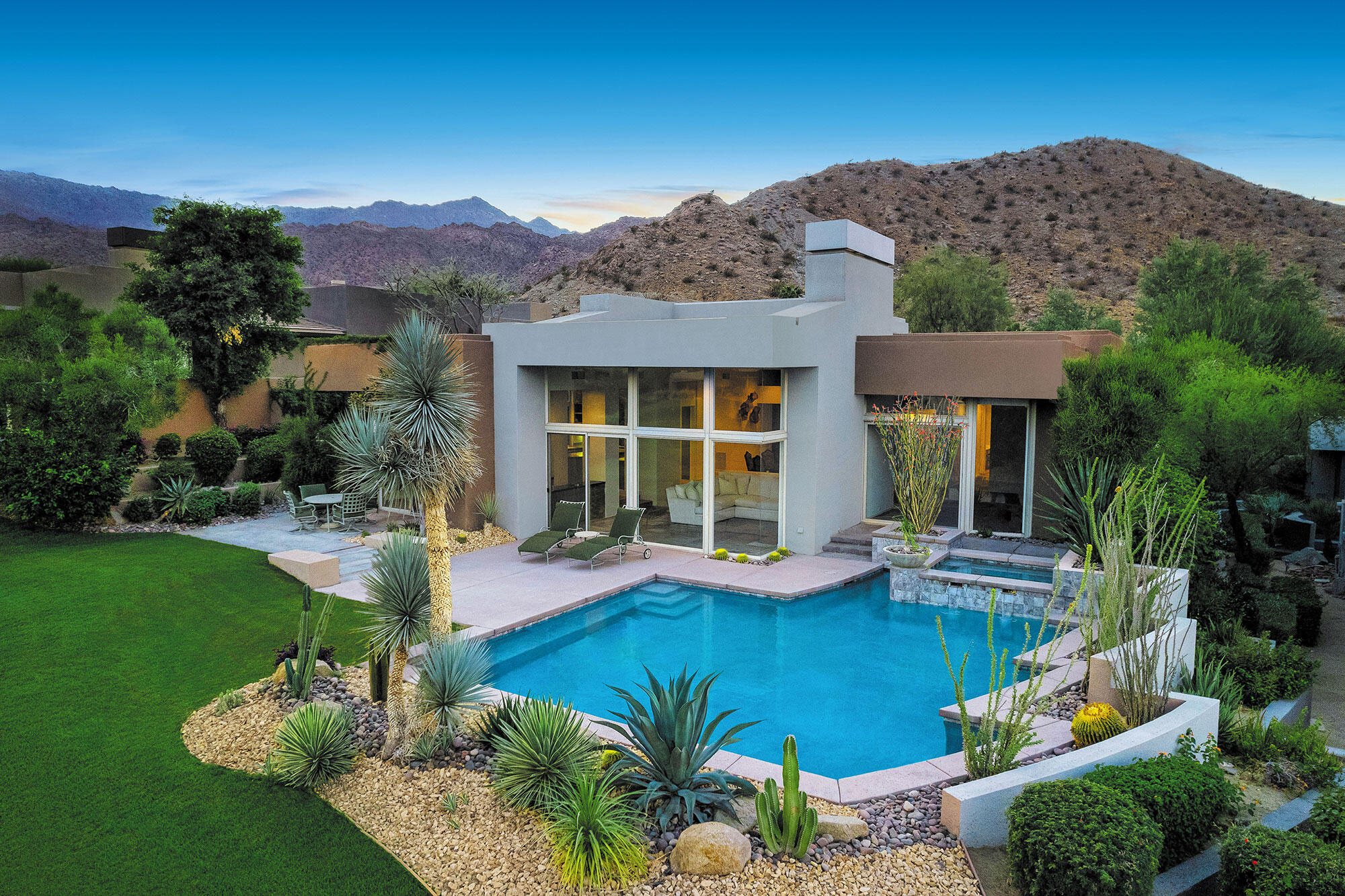 a front view of a house with swimming pool lawn chairs and large tree