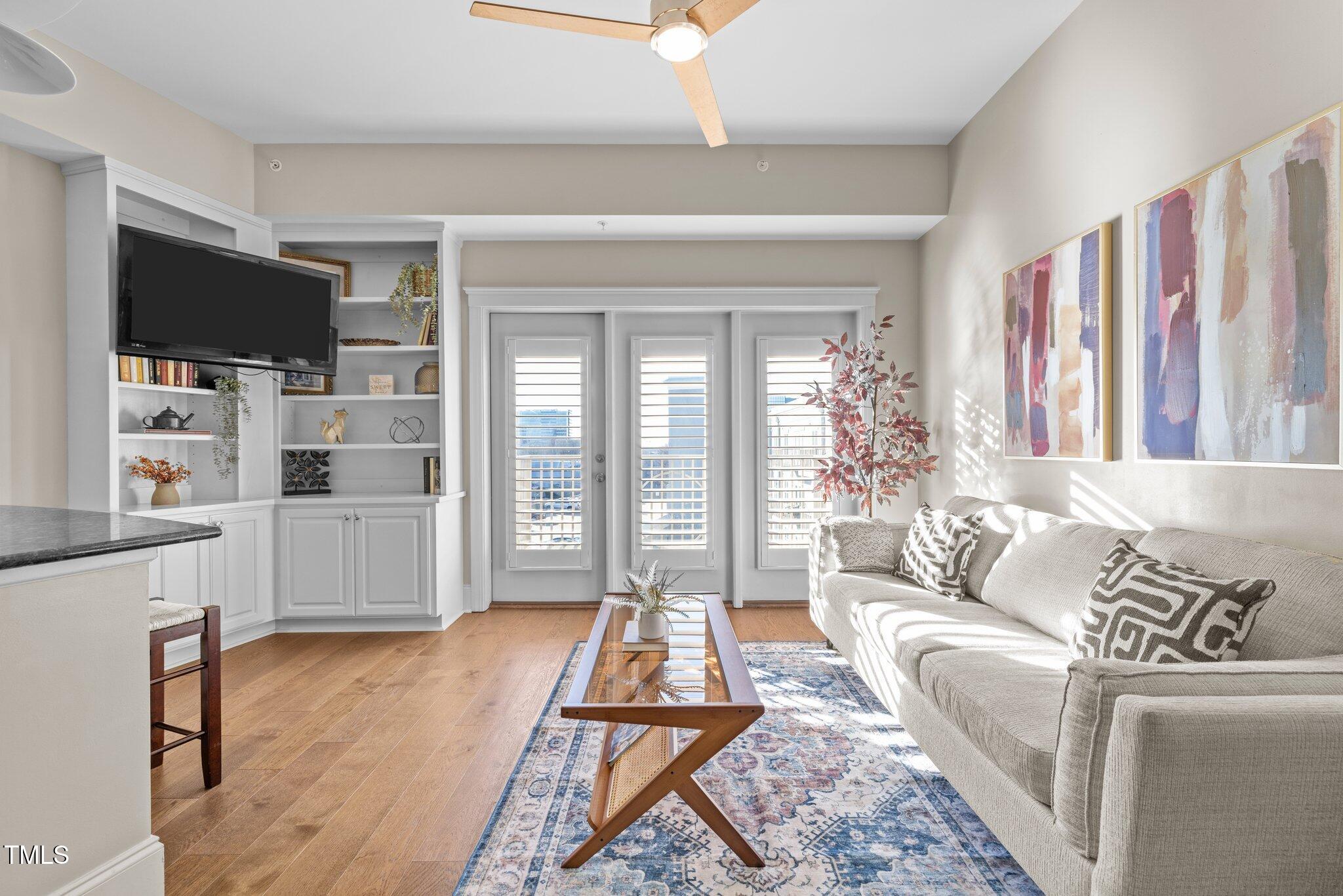 a living room with furniture a flat screen tv and a floor to ceiling window