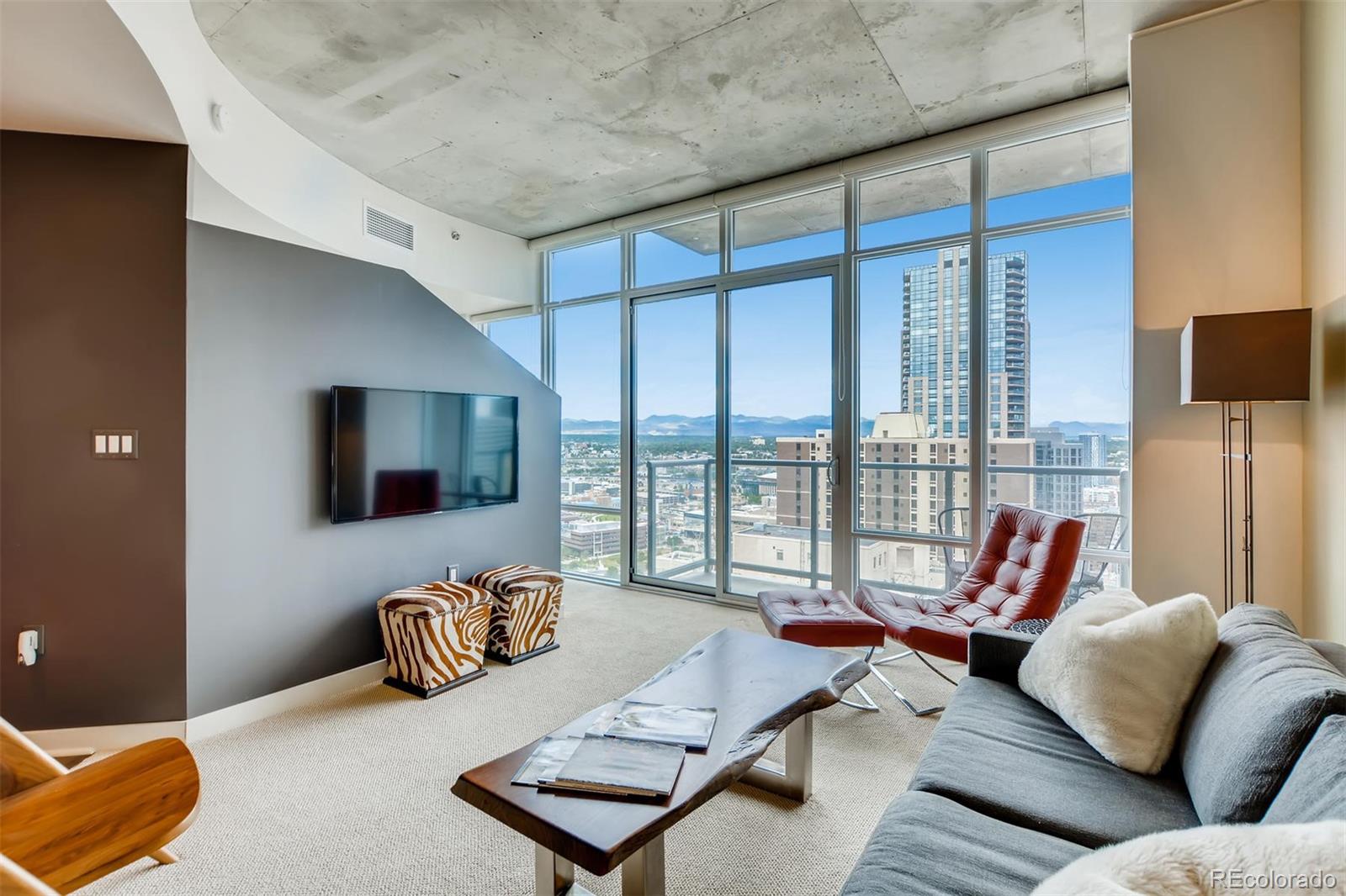 a living room with furniture floor to ceiling window and a flat screen tv