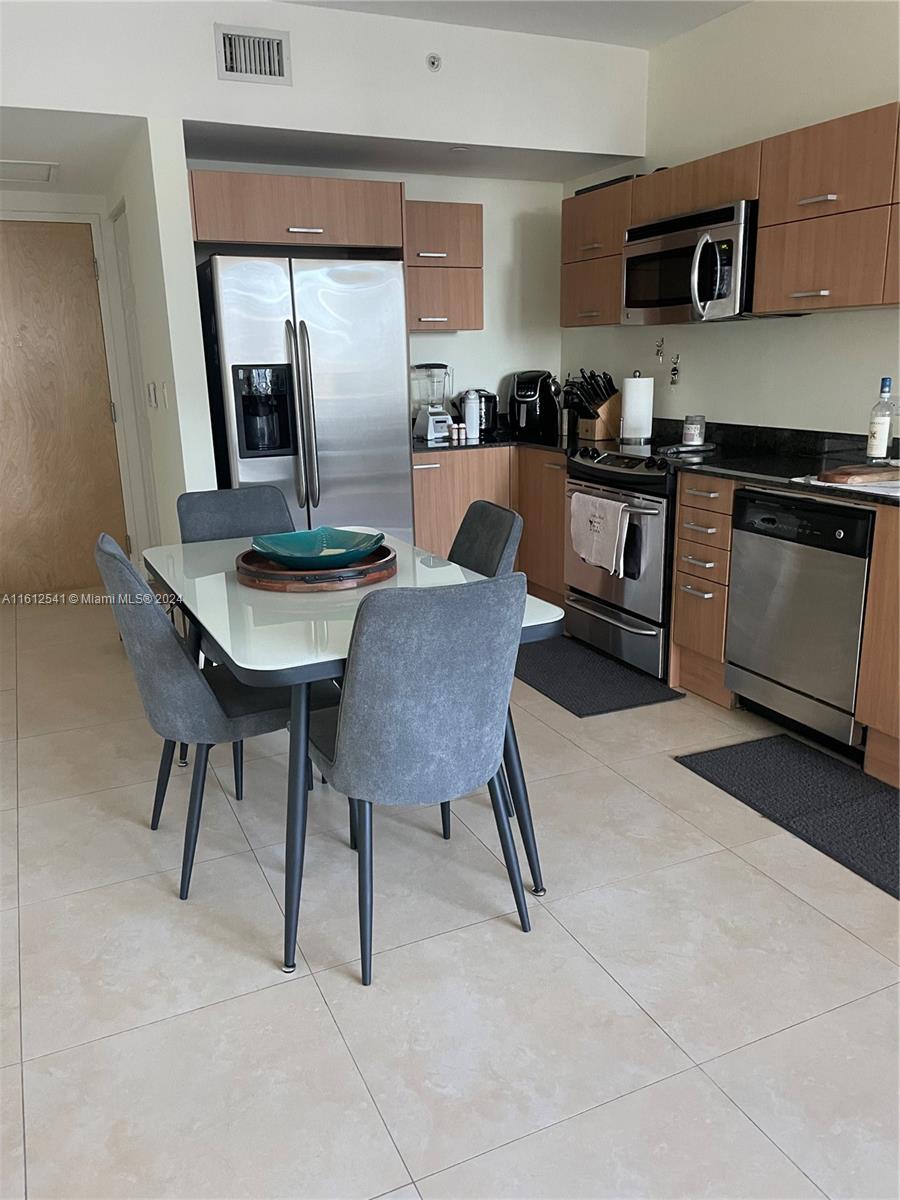 a kitchen with stainless steel appliances kitchen island a table chairs in it and wooden floors